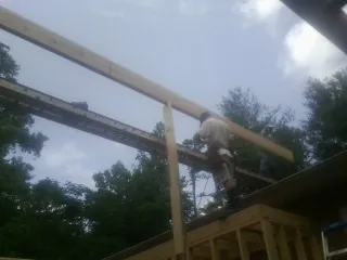 Carpenter setting a ridge beam over a new addition frame — Ice Dam Removal by Roofing Brothers in Mathiston