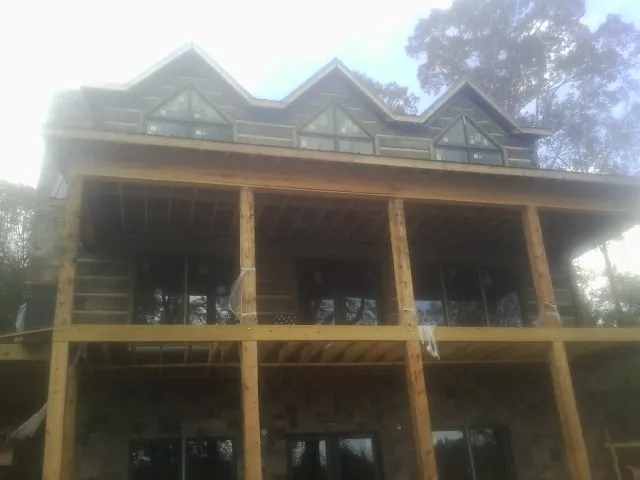 Dormers and porch framing on a large log home under construction — Roof Coating work by our crew in Mathiston