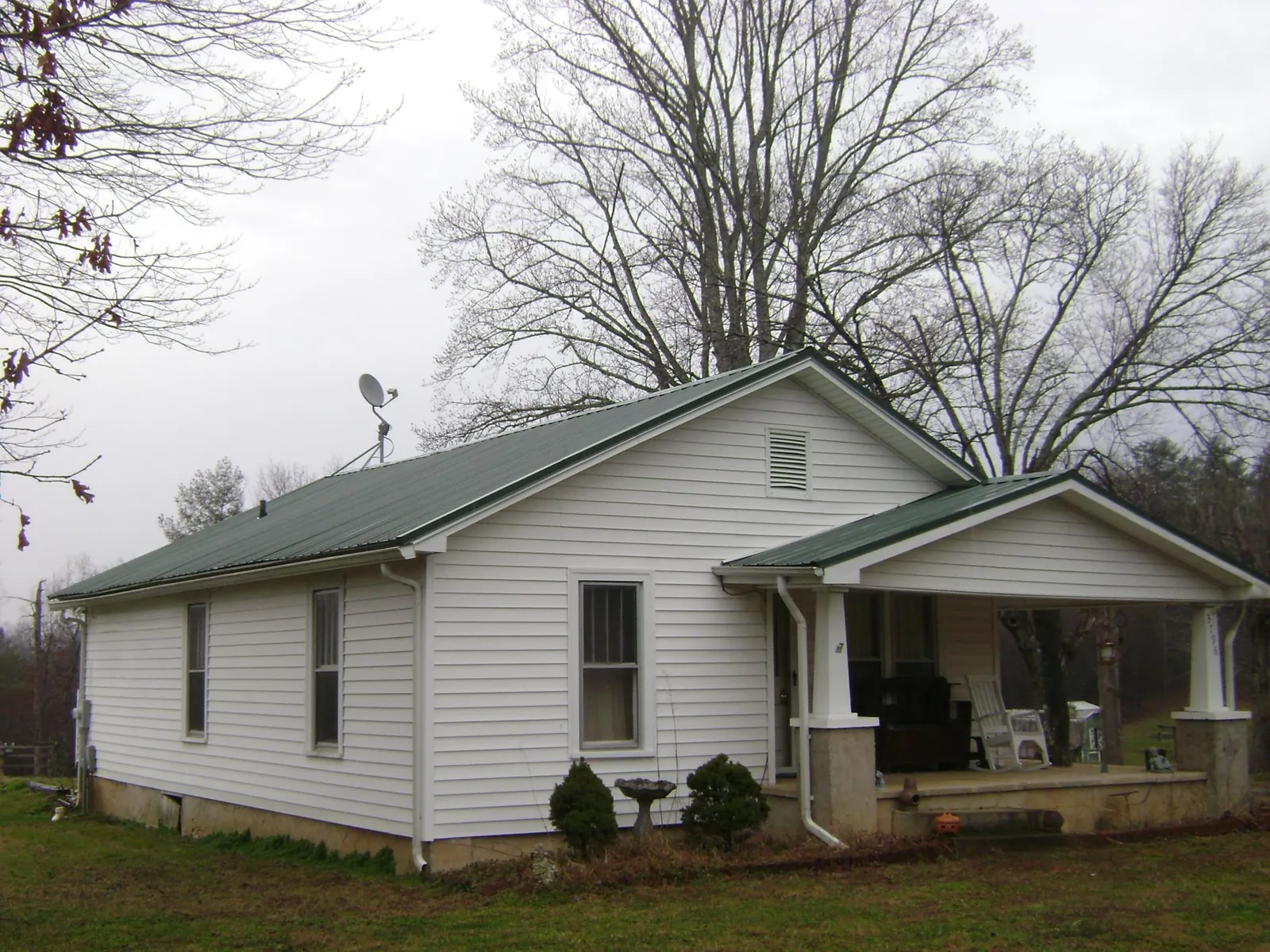 Green metal roof on a white bungalow with a side porch in Mathiston