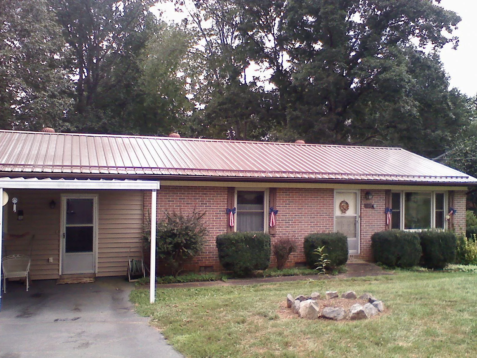 Bronze metal roof and carport on a brick ranch home — Roof Repair work by our crew in Mathiston