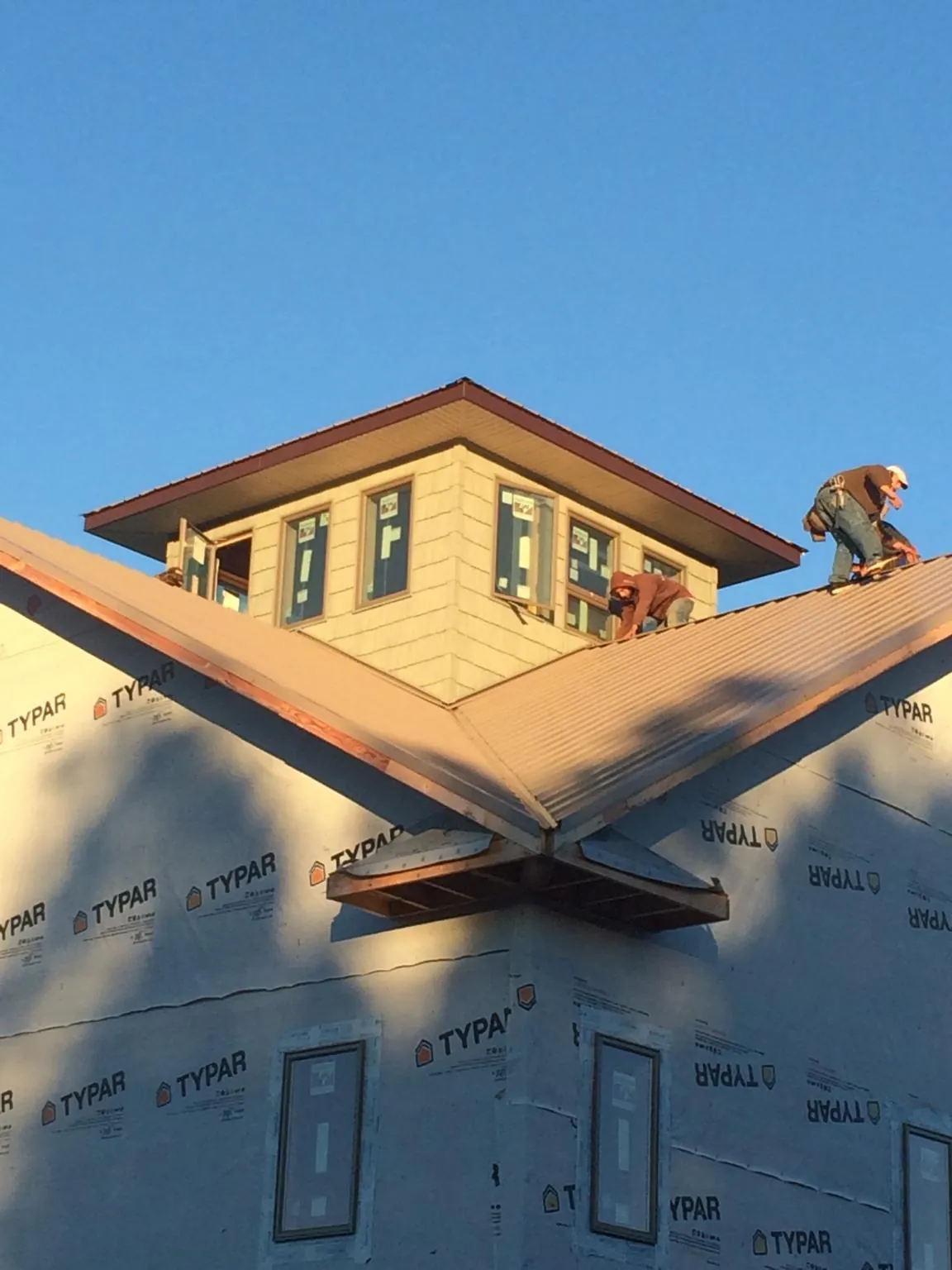 Roofers working around a rooftop cupola on a new metal roof at sunset — Roof Waterproofing in Mathiston by Roofing Brothers